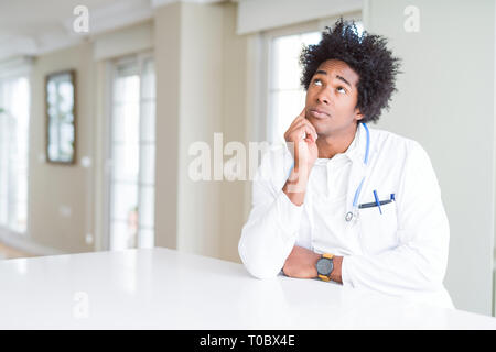 Americano africano uomo medico presso la clinica con la mano sul mento pensando di domanda, pensieroso espressione. Sorridente con premurosa faccia. Concetto di dubbio. Foto Stock