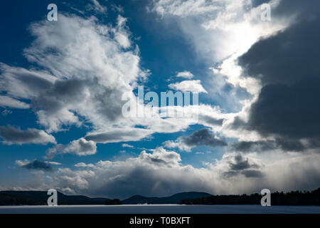 Nuvole temporalesche muovendo in su il sole e la copertura di un profondo cielo blu con nuvole bianche. Foto Stock