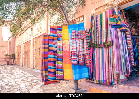 Colorate marocchine tradizionali sciarpe e scialli appeso a un albero per la vendita in un negozio di souvenir di Ouarzazate, Marocco. Foto Stock