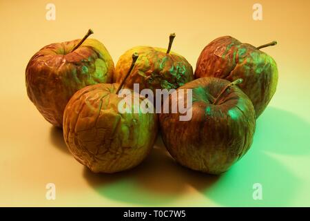 Chiudere fino a cinque mele marce isolate su sfondo colorato Foto Stock