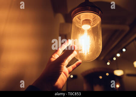 La mano di raggiungere per un vintage lampadina. Foto Stock