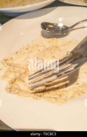 Un osso di cina la piastra sinistra dopo cibo mangiato con un cucchiaio e una forchetta in un ristorante. La piastra non lavate. Foto Stock