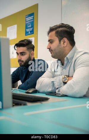 Gli studenti internazionali e gli alunni nella stanza del computer di un College / Università studiare e tramite il computer desktop Foto Stock