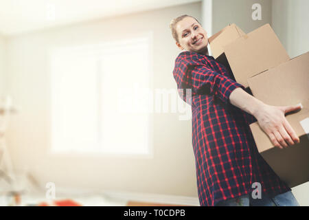 Traslocare in una nuova casa - sorridente giovane donna che trasportano le caselle. spazio copia Foto Stock