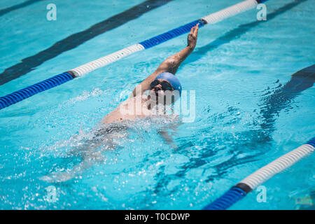 Giovane maschio caucasico nuotatore nuoto dorso in piscina Foto Stock