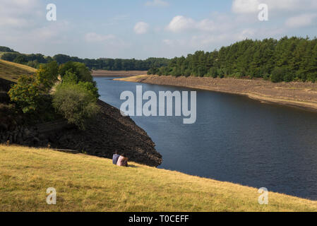 Coppia alla ricerca sul fondo del serbatoio nella valle Longdedale, Tintwistle, Derbyshire, in Inghilterra. Una soleggiata mattina d'estate. Foto Stock