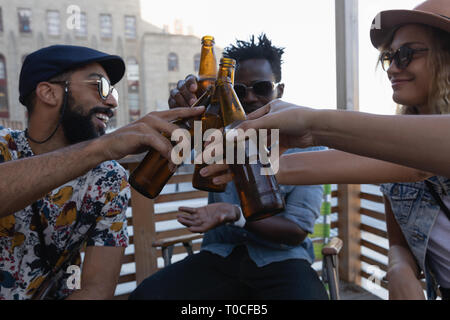 Gruppo di amici la tostatura con bottiglie di birra in casa in balcone Foto Stock