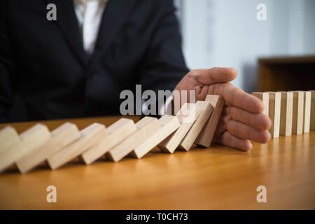 Imprenditore si ferma mano domino capovolta continua nel senso che ostacolavano il fallimento aziendale. Stop Over questo fallimento aziendale concetto. Foto Stock