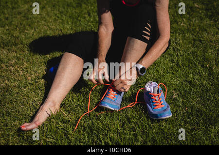 Attiva donna senior legatura di lacci delle scarpe nel parco Foto Stock