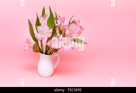 Bouquet di fiori di colore rosa su sfondo rosa. Fiori di Primavera in un vaso di bianco. Il minimalismo Foto Stock