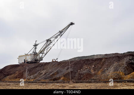 Grande escavatore a piedi in previsione del materiale rotabile il trasporto di sovraccaricare per lo stoccaggio in discariche. Paesaggio industriale dopo la distruzione di n Foto Stock