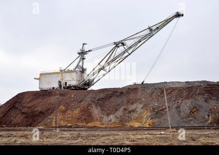 Grande escavatore a piedi in previsione del materiale rotabile il trasporto di sovraccaricare per lo stoccaggio in discariche. Paesaggio industriale dopo la distruzione di n Foto Stock