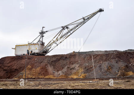 Grande escavatore a piedi in previsione del materiale rotabile il trasporto di sovraccaricare per lo stoccaggio in discariche. Paesaggio industriale dopo la distruzione di n Foto Stock