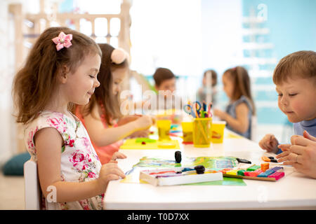 Scuola materna bambini di apprendimento di gruppo arti e mestieri in sala giochi con interesse Foto Stock