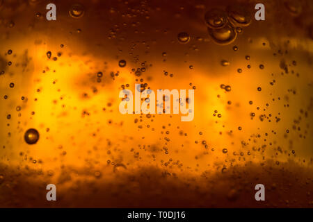 Foto macro di liquido ambrato con bolle d'aria brillanti e texture dorata Foto Stock