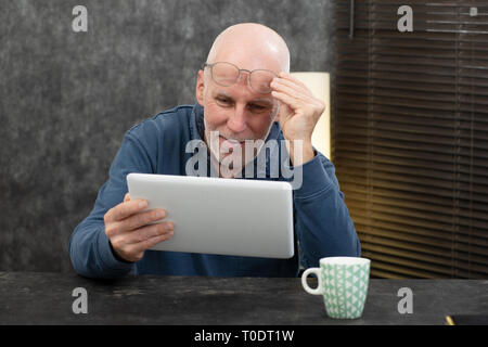 Un imprenditore senior utilizzando tablet, egli sta avendo difficoltà e problemi di visione Foto Stock