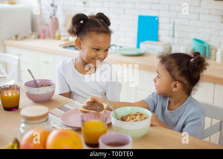 Carino piccolo femmine aventi una gustosa colazione insieme Foto Stock