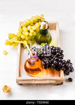 Foto dal di sopra del vassoio di legno con il verde e l'uva nera, due bottiglie di succo di frutta Foto Stock