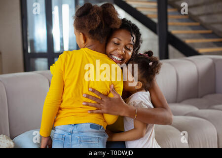 Positivo il piacere giovane donna che abbraccia i suoi figli Foto Stock