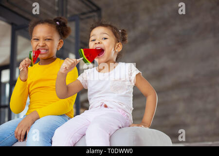 Gioiosa bambina mangiando caramelle con piacere Foto Stock