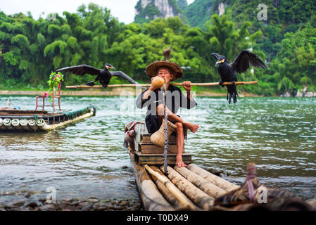 Yangshuo, Cina - 27 Luglio 2018: Tradizionale cormorano pescatore per un bambù zattere sul fiume Li in Yangshuo vicino a Guilin in Cina Foto Stock
