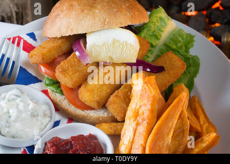 Inglese tipici snack per il pranzo di pesce le dita in un panino, patata dolce patate fritte servite con ketchup e il tartaro. Foto Stock