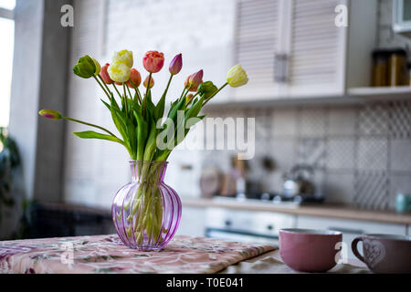 Vaso di vetro con bouquet di tulipani bellissimo sul muro di mattoni in background. Foto Stock