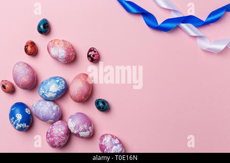 Pasqua uova colorate di bianco e blu con nastro su sfondo rosa. Spazio per il testo, concetto di sfondo di Pasqua Foto Stock