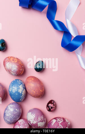 Gioioso della Pasqua uova colorate di bianco e blu con nastro su sfondo rosa. Spazio per il testo, concetto di sfondo di Pasqua Foto Stock