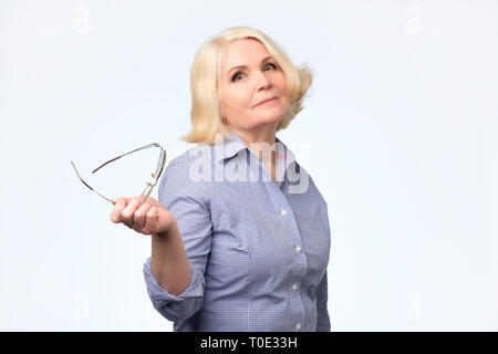 Senior caucasian donna con capelli biondi in bianco e giallo sorridente maglione Foto Stock