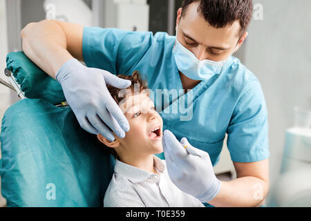 Dentista considera i denti di un adolescente in una clinica dentale Foto Stock