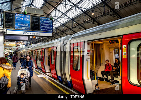 Due ragazze sedute su un treno Stock District Line S7 in attesa della chiusura delle porte alla stazione della metropolitana di Earls Court, Londra, Regno Unito Foto Stock