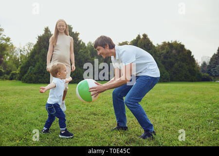Donna incinta e uomo giocando con il figlio in posizione di parcheggio Foto Stock
