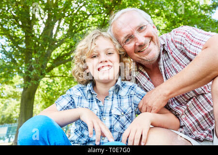 Happy boy insieme con il suo nonno in natura in estate Foto Stock