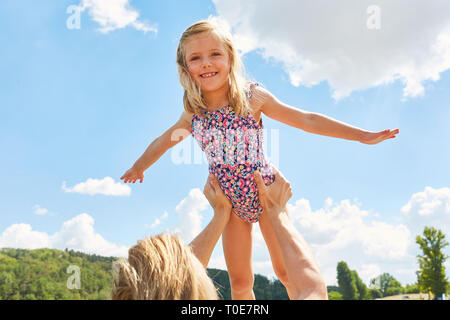 Padre figlia solleva in aria e permette il suo volo durante le vacanze estive Foto Stock