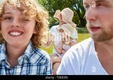 Famiglia con due bambini rende la gita in canotto sulle sponde di un lago in estate Foto Stock