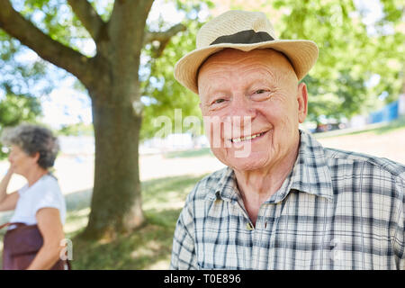 Gentile uomo senior con cappello di paglia si è ritirato in estate in un parco Foto Stock