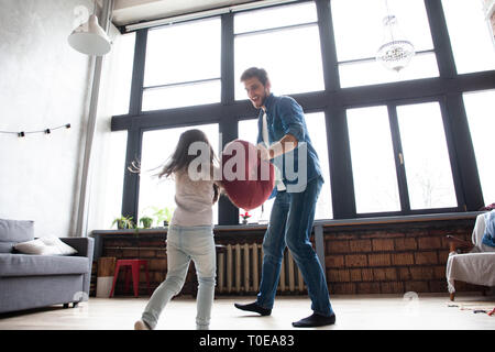 Il padre e il figlio insieme giocando. Ragazza e papà divertendosi e combattere i cuscini. Vacanza con la famiglia e stare insieme. Foto Stock