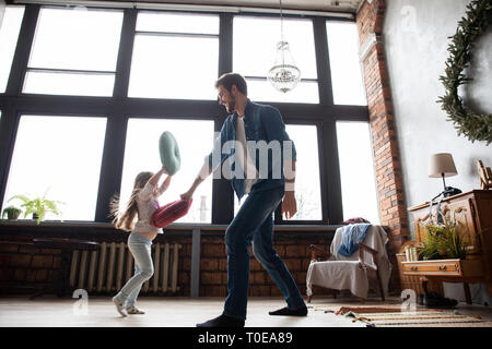 Il padre e il figlio insieme giocando. Ragazza e papà divertendosi e combattere i cuscini. Vacanza con la famiglia e stare insieme. Foto Stock