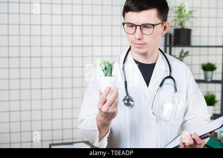 Scienziato conduce esperimenti con una pianta verde Foto Stock