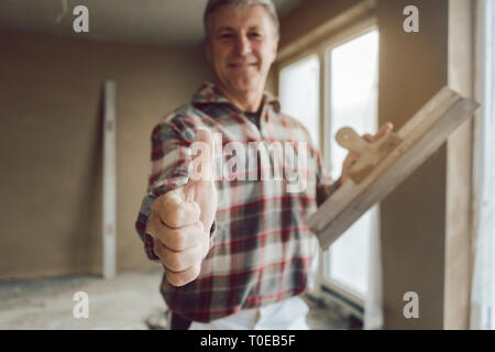 Stuccatore dando Thumbs up nell'interno del recentemente costruita casa Foto Stock