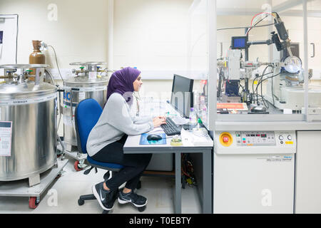 Una donna musulmana utilizza le attrezzature scientifiche in un laboratorio di ricerca, presso la University of Sussex indossando un tradizionale hijab. Foto Stock