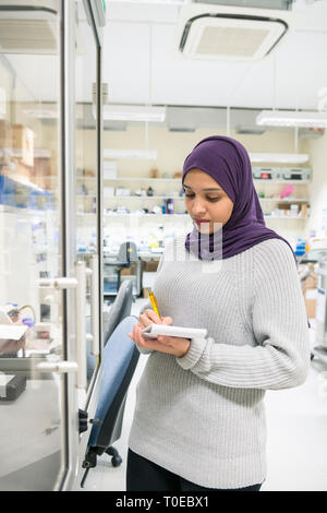 Una donna musulmana utilizza le attrezzature scientifiche in un laboratorio di ricerca, presso la University of Sussex indossando un tradizionale hijab. Foto Stock