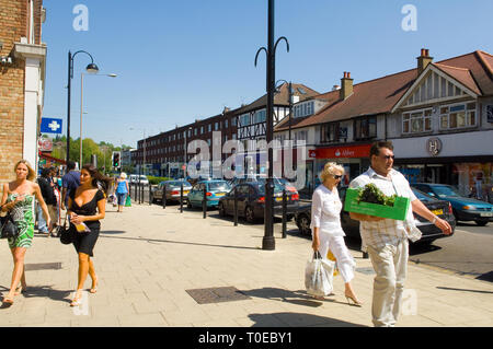 Scena di strada di persone a piedi giù per la strada di botesdale, Essex. Un uomo in primo piano è di trasportare una scatola. Foto Stock