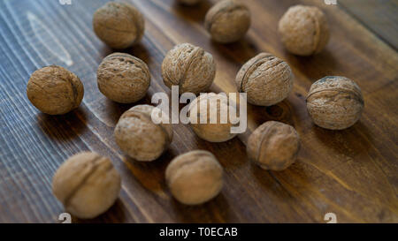 Materie organiche di noci comuni in guscio sul vecchio brown sfondo in legno in stile rustico. I dadi del raccolto dal paese. Ingredienti salutari per la dieta. Close up. Foto Stock
