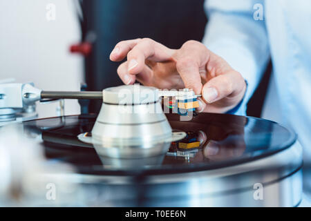 Donna mettendo ago sul disco in vinile sul giradischi Foto Stock