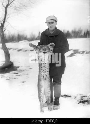 Un giovane uomo visualizza il suo trofeo Maine bobcat o lynx, ca. 1915. Foto Stock