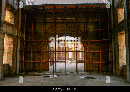 La costruzione dell'edificio. Grande Arco di mattoni. Costruzione di ponteggi su una casa in costruzione. Pavimento in calcestruzzo Foto Stock