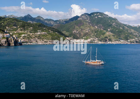 Una barca appoggio all-ancoraggio nel blu del mare appena fuori la costa di Amalfi, vicino a Minori, Italia Foto Stock