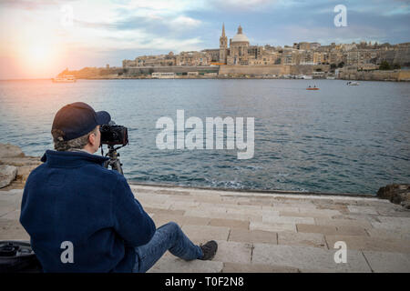 L'uomo prendendo foto di paesaggi con una telecamera e un treppiede, Valletta, Malta. Foto Stock